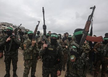 Los combatientes de Hamas llevan rifles en una entrega de rehenes en Gaza.