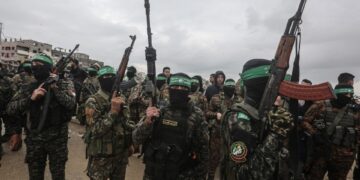 Los combatientes de Hamas llevan rifles en una entrega de rehenes en Gaza.
