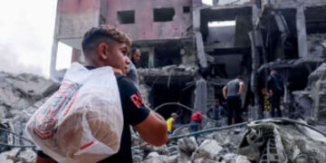 Una juventud palestina lleva pan en medio de los escombros del centro de la ciudad de Khan Yunis en la franja del sur de Gaza después de bombardeos israelíes el 10 de octubre de 2023.