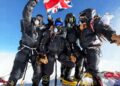 Cuatro escaladores británicos en el Monte Everest Summit, sosteniendo una bandera del Reino Unido.
