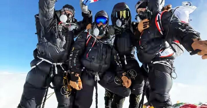Cuatro escaladores británicos en el Monte Everest Summit, sosteniendo una bandera del Reino Unido.