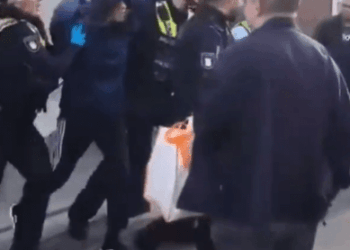 Oficiales de policía que arrestaron a una persona encapuchada.