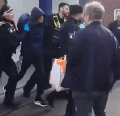 Oficiales de policía que arrestaron a una persona encapuchada.