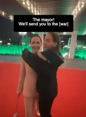 Una mujer abrazando un recorte de tamaño natural del alcalde en una alfombra roja.