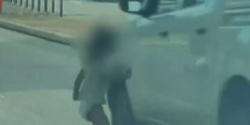 Niño pequeño en pañales corriendo a una carretera.