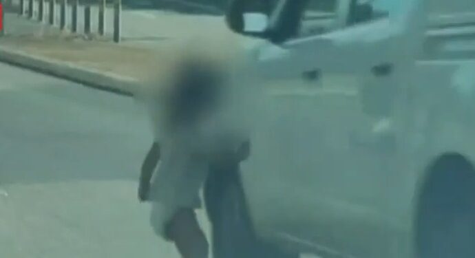 Niño pequeño en pañales corriendo a una carretera.