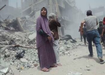 Los civiles palestinos pasan más allá de las estructuras y los escombros colapsados ​​después de un ataque aéreo israelí en Gaza, el 17 de mayo de 2025.