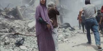 Los civiles palestinos pasan más allá de las estructuras y los escombros colapsados ​​después de un ataque aéreo israelí en Gaza, el 17 de mayo de 2025.