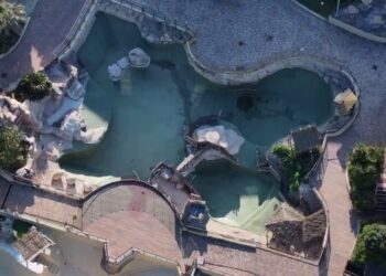 Vista aérea de un parque marino abandonado con dos orcas y doce delfines.