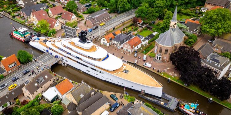 Vista aérea de un mega yate que pasa a través de un canal estrecho en un pueblo holandés.