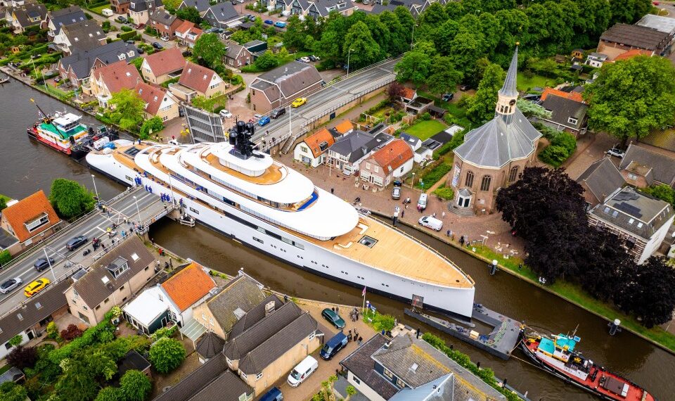 Vista aérea de un mega yate que pasa a través de un canal estrecho en un pueblo holandés.