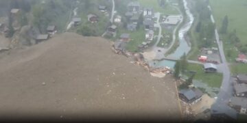 Vista aérea de una avalancha que destruye edificios en un pueblo.
