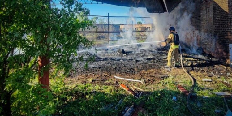 Un bombero extinguiendo un incendio en un edificio dañado.