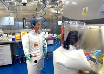 Dos científicos en trajes protectores que trabajan en un laboratorio.