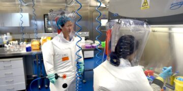 Dos científicos en trajes protectores que trabajan en un laboratorio.