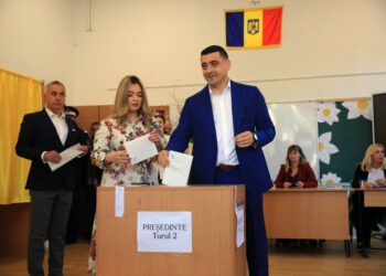 Un hombre con un traje azul que arroja una boleta en una elección presidencial rumana.