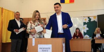 Un hombre con un traje azul que arroja una boleta en una elección presidencial rumana.