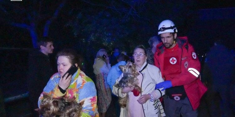Personal de emergencia que evaciona a los residentes y sus perros de un edificio dañado.