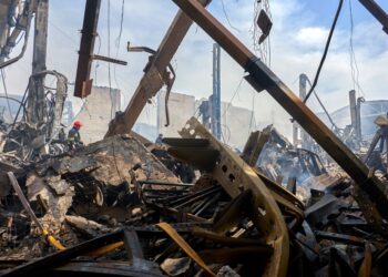 Los bomberos en el sitio de un almacén dañado después de un ataque con aviones no tripulados.