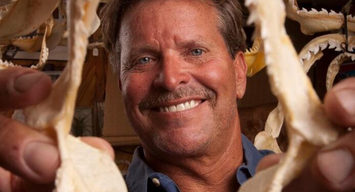 Un hombre sosteniendo una gran mandíbula de tiburones.