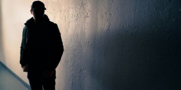 Silueta de un hombre sospechoso en un callejón oscuro.