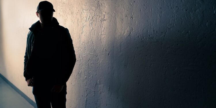 Silueta de un hombre sospechoso en un callejón oscuro.