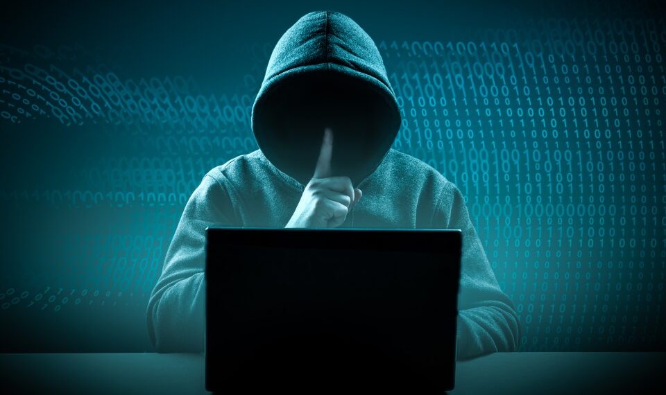 una persona en una sudadera con capucha sentada frente a una computadora portátil