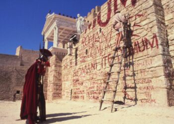 Una quieta de la vida de Brian de Monty Python que muestra un muro con graffiti y un soldado romano.