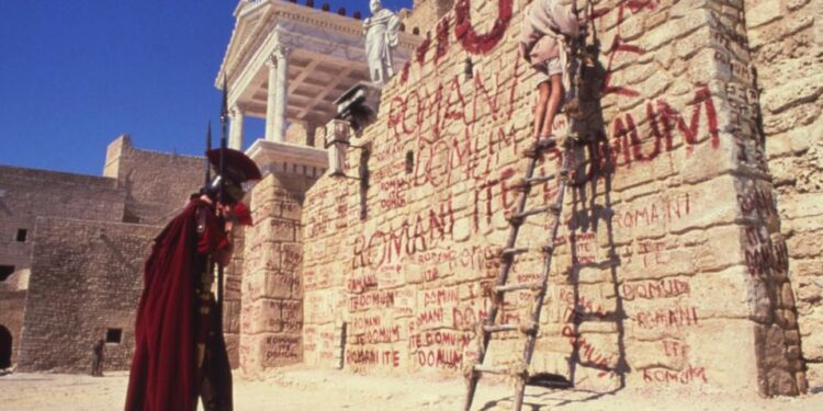 Una quieta de la vida de Brian de Monty Python que muestra un muro con graffiti y un soldado romano.