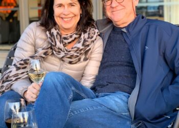 Alan y Karen Carter sentados juntos al aire libre con vino.