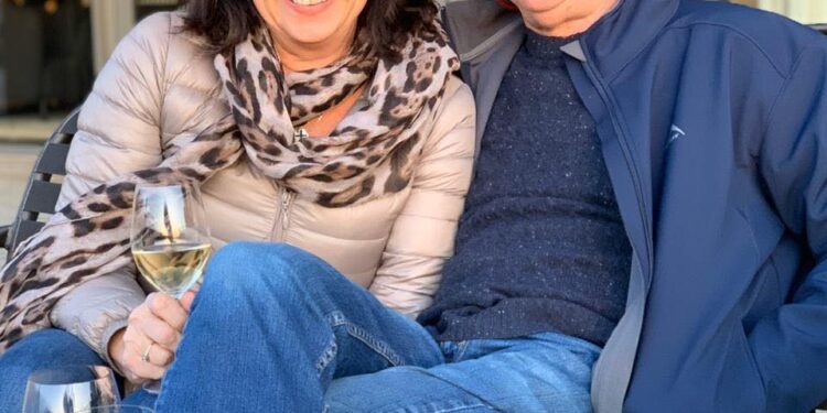 Alan y Karen Carter sentados juntos al aire libre con vino.