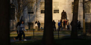 La gente se reúne para tomar fotos con la estatua de John Harvard en la Universidad de Harvard el 17 de abril de 2025 en Cambridge, Massachusetts.