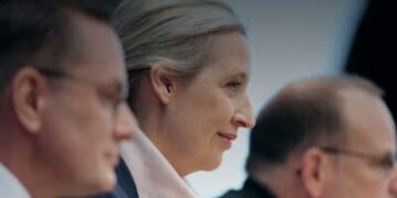 Tres alemanes se sientan uno al lado del otro en una mesa