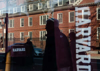 La Universidad de Harvard se refleja en la ventana de una tienda de mercancías al otro lado de la calle de la escuela el 17 de abril de 2025 en Cambridge, Massachusetts.