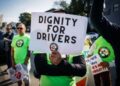 Una persona con una camisa verde sostiene un letrero que lee "Dignidad para conductores" con el logotipo de los conductores de viaje compartido debajo del texto
