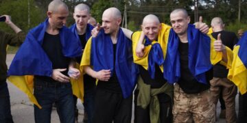 Prisioneros de guerra ucranianos cubiertos en banderas ucranianas después de un intercambio de prisioneros.