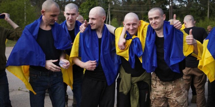 Prisioneros de guerra ucranianos cubiertos en banderas ucranianas después de un intercambio de prisioneros.