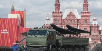 Vehículo blindado que transporta drones en un desfile militar.