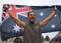 Un corredor que sostiene una bandera australiana después de establecer un nuevo récord mundial para la carrera  rápida en Australia.