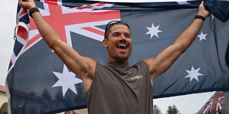 Un corredor que sostiene una bandera australiana después de establecer un nuevo récord mundial para la carrera rápida en Australia.