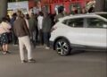 Captura de pantalla de una multitud de personas se reunió alrededor de un autobús y un SUV blanco.