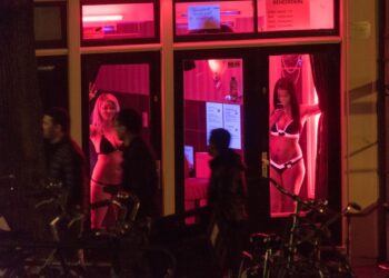 Las trabajadoras sexuales se ven detrás de las ventanas en el Distrito de Luz Roja en Amsterdam, Países Bajos, 24 de abril de 2015. El distrito de luz roja de la ciudad se encuentra en una red de callejones que contienen aproximadamente trescientas cabañas de una habitación alquiladas por prostitutas que ofrecen sus servicios sexuales desde detrás de una ventana o puerta de vidrio, típicamente iluminadas con luces rojas. Amsterdam es uno de los destinos turísticos populares de Europa, que recibe de 4.63 millones de visitantes internacionales anualmente. (Foto de Horacio Villalobos/Corbis a través de Getty Images)