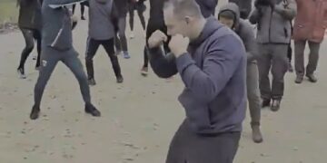 Man Shadow Boxing en un parque con una multitud mirando.
