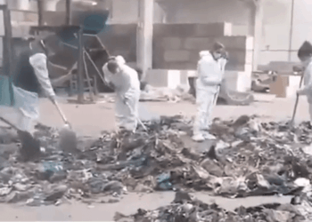 Personas en trajes protectores que limpian los escombros.