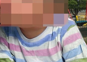 La cara del niño está borrosa, con una camisa a rayas pastel.