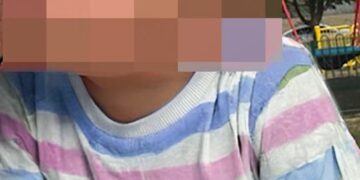 La cara del niño está borrosa, con una camisa a rayas pastel.