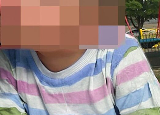 La cara del niño está borrosa, con una camisa a rayas pastel.