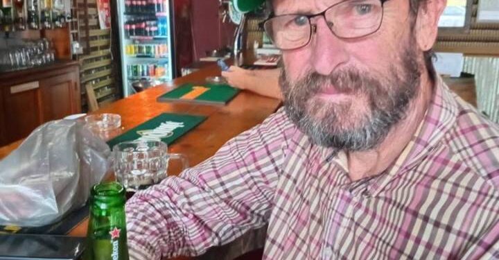Un hombre con una gorra verde Heineken se encuentra en un bar con una cerveza Heineken.