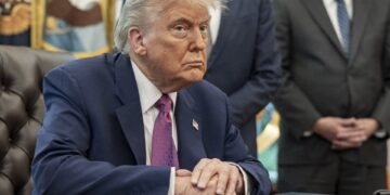 El presidente Donald Trump sentado en una mesa en la Oficina Oval.