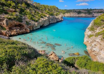 Calo des Moro Beach con agua turquesa cristalina y personas nadando.
